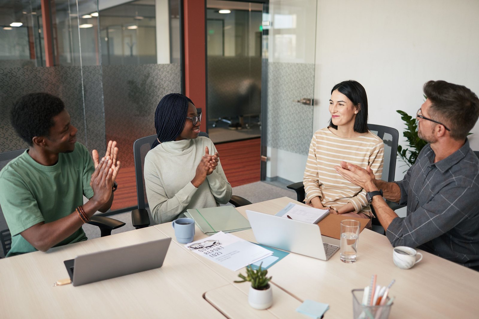 A small team at a meeting table with laptops and a printed report