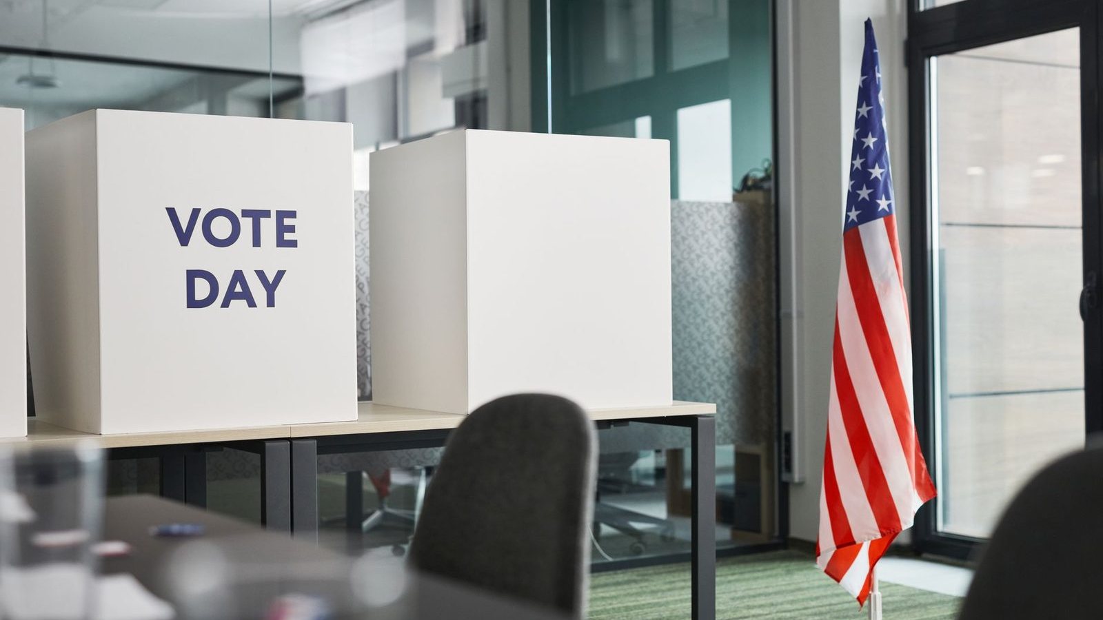 Voting booths beside an American flag in a polling place